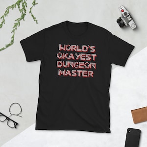 May include: Black t-shirt with the text "WORLD'S OKAYEST DUNGEON MASTER" in red and white.