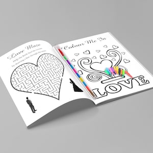 May include: Open wedding activity book with a heart-shaped maze and coloring pages. The text on the left page reads "Love Maze" and the right page says "Colour Me In LOVE". A set of colorful markers is included.