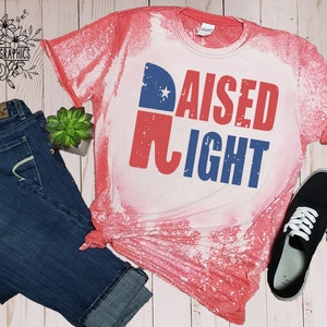 May include: A red, white, and blue bleached t-shirt with the text "RAISED RIGHT" and a red, white, and blue elephant graphic.