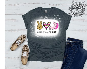 May include: A dark grey t-shirt with a white bleach design featuring a peace sign, a heart with pink and gold stripes, and a pink and white stomach with the text "peace love vsg".