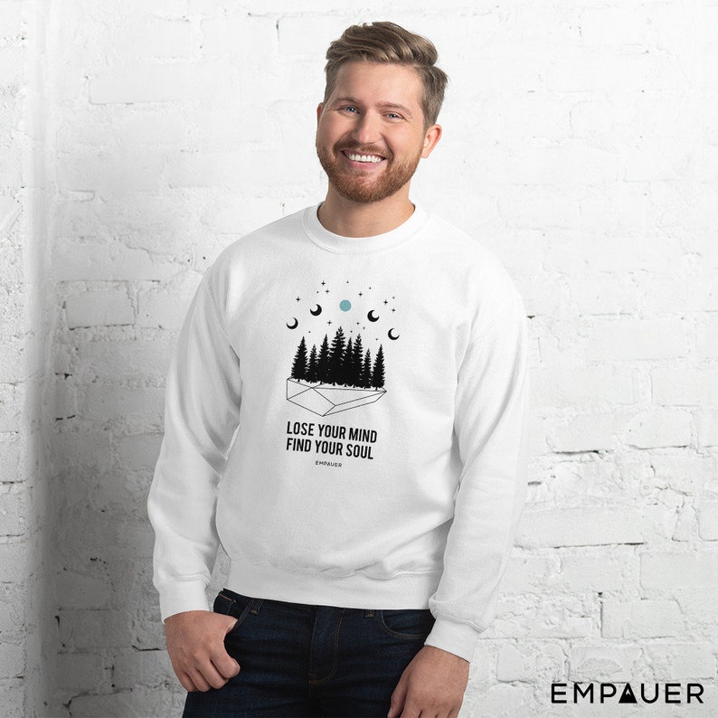 K&ouml;nnte beinhalten: Wei&szlig;es Sweatshirt mit schwarzer Grafik eines Waldes, Mondphasen und Sternen. Der Text "LOSE YOUR MIND FIND YOUR SOUL" ist unter der Grafik aufgedruckt. Der Markenname "EMPAUER" ist unten rechts aufgedruckt.