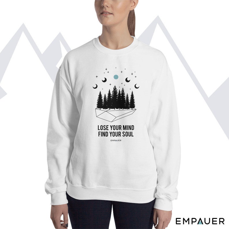 K&ouml;nnte beinhalten: Wei&szlig;es Sweatshirt mit einer schwarzen Grafik von Wald, Mondphasen und Sternen. Der Text "LOSE YOUR MIND FIND YOUR SOUL" ist darunter gedruckt. Der Markenname "EMPAUER" ist darunter gedruckt.