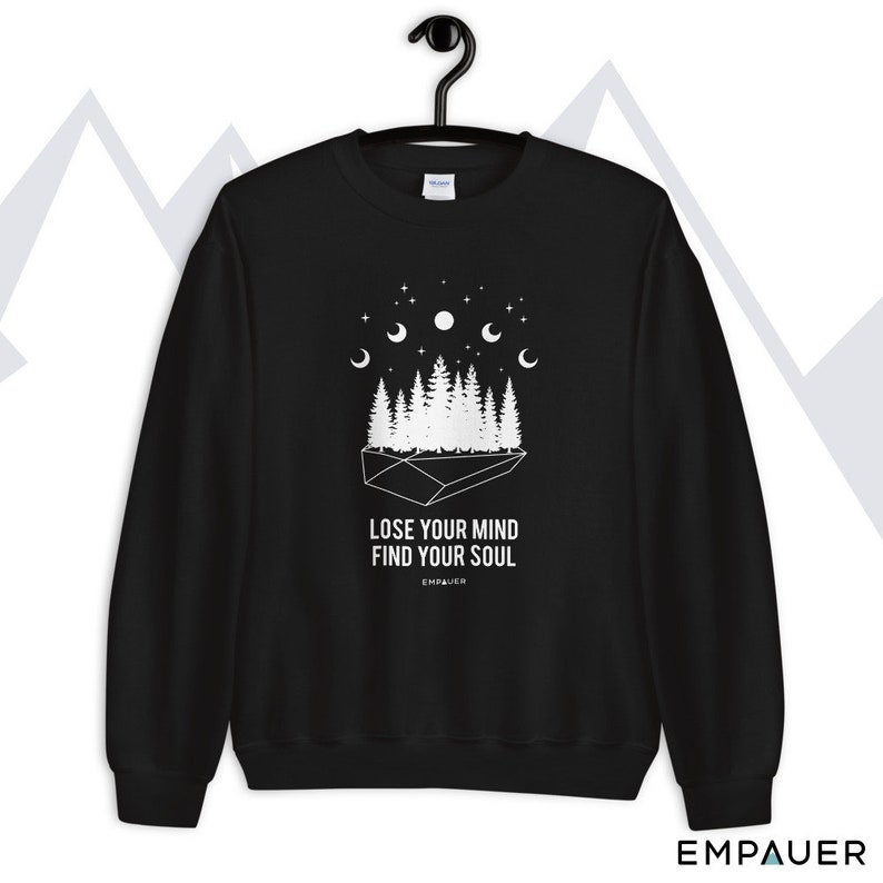 K&ouml;nnte beinhalten: Schwarzes Sweatshirt mit wei&szlig;er Grafik eines Waldes, Sternen und Halbmonden. Der Text "LOSE YOUR MIND FIND YOUR SOUL" ist unter der Grafik aufgedruckt. Der Markenname "EMPAUER" ist unten aufgedruckt.