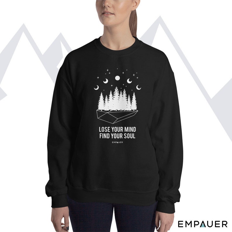 K&ouml;nnte beinhalten: Schwarzes Sweatshirt mit wei&szlig;er Grafik eines Waldes, Mondphasen und Sternen. Der Text "LOSE YOUR MIND FIND YOUR SOUL" ist unter der Grafik aufgedruckt. Der Markenname "EMPAUER" ist unten aufgedruckt.