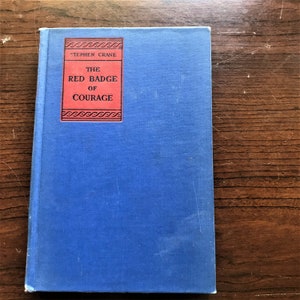 May include: A blue hardcover book with the title "The Red Badge of Courage" by Stephen Crane on the spine.