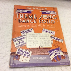 May include: A vintage orange, purple, and blue booklet titled "Theme Song Dance Folio" featuring photographs of the principal stars of the singing-talking pictures. The booklet includes songs such as "Let Me Have My Dreams", "Hard to Get", "My Song of the Nile", "Am I Blue?", "Smiling Irish Eyes", and "Wishing and Waiting for Love".