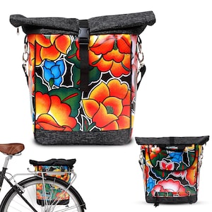 Puede incluir: Una bolsa de bicicleta negra y gris con estampado floral y cierre enrollable. La bolsa tiene una correa negra y está unida a una bicicleta.