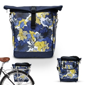 Puede incluir: Una mochila de estampado floral azul y amarillo con cierre de rollo. La mochila tiene una correa para el hombro y se puede usar como bolsa de bicicleta.