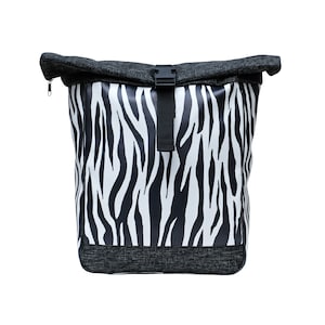 May include: A black and white zebra-print backpack with a black zipper and buckle closure. The backpack has a roll-top design and is made of a durable material.