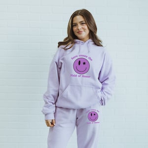 May include: A lavender hoodie and sweatpants set with a smiling face graphic and the text "here comes the Maid of Honor".