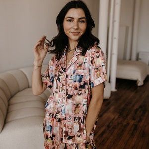 May include: A pink and white pyjama set featuring a print of various dog breeds. The set includes a short-sleeved shirt and shorts.