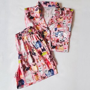 May include: Pink pyjamas with a dog print and white monogram "ACB".