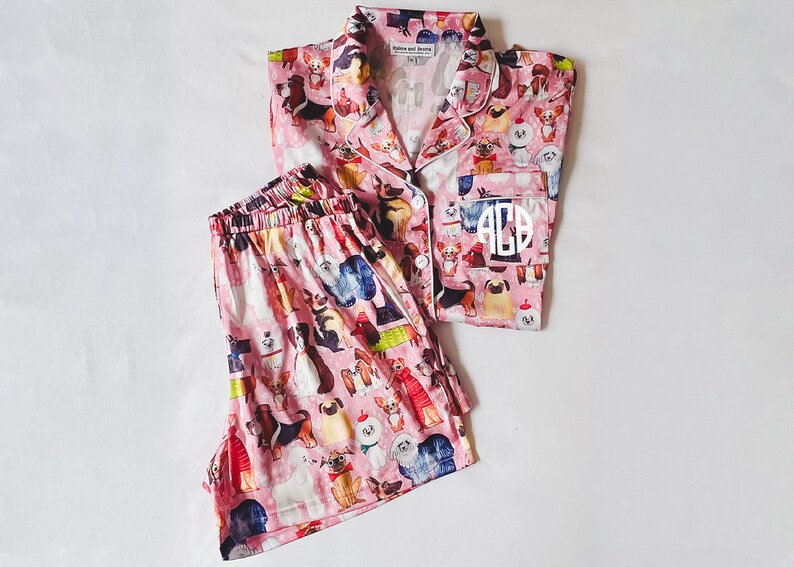 May include: Pink pyjamas with a dog print and white monogram "ACB".