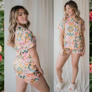 May include: A pink and green floral print pyjama set with a short-sleeved top and shorts. The top has a button-up front and a collar.
