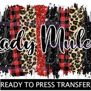 May include: A graphic design with the words "Lady Mules" in a script font, set against a backdrop of red plaid, leopard print, and red glitter stripes. The words "READY TO PRESS TRANSFER" are at the bottom.