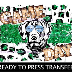 May include: A graphic design featuring a Dalmatian dog wearing sunglasses with the word "Pointers" on them. The words "GAME DAY" are in marquee-style lettering. The background includes green glitter and a black and white leopard print.