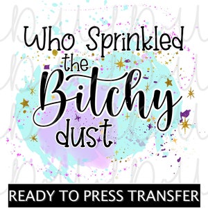 May include: A ready to press transfer design with a watercolor background in shades of blue and purple. The design features gold glitter and the text "Who Sprinkled the Bitchy dust".
