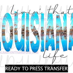 May include: A white background with the words "Livin' that Louisiana Life" in a stylized font. The word "Louisiana" is filled with a scenic image of a lake and trees. The text "READY TO PRESS TRANSFER" is at the bottom.