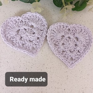 May include: Two crocheted lavender heart-shaped coasters. The coasters are made with a delicate openwork pattern. The text "Ready made" is visible below the coasters.