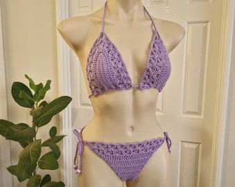 May include: A purple crochet bikini top and bottom. The top is a triangle style with a tie at the neck and back. The bottom is a high-waisted style with ties on the sides.