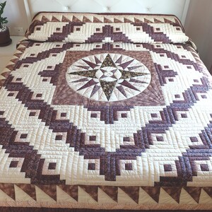 Könnte beinhalten: Eine Bettdecke mit einem zentralen Kompassstern-Motiv, umgeben von geometrischen Mustern in Creme-, Beige- und Dunkelbrauntönen. Das Design umfasst aufwendig zusammengesetzte Quadrate und Dreiecke mit detaillierten Steppnähten im Stoff.