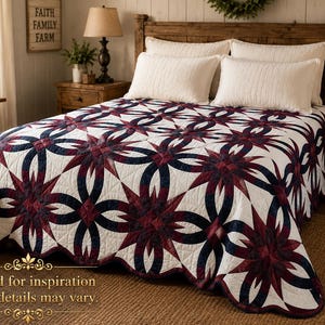 May include: A white quilt with a repeating pattern of navy blue interlocking rings and burgundy starbursts. The quilt is on a wooden bed frame with white pillows. The room has a rustic, farmhouse style.