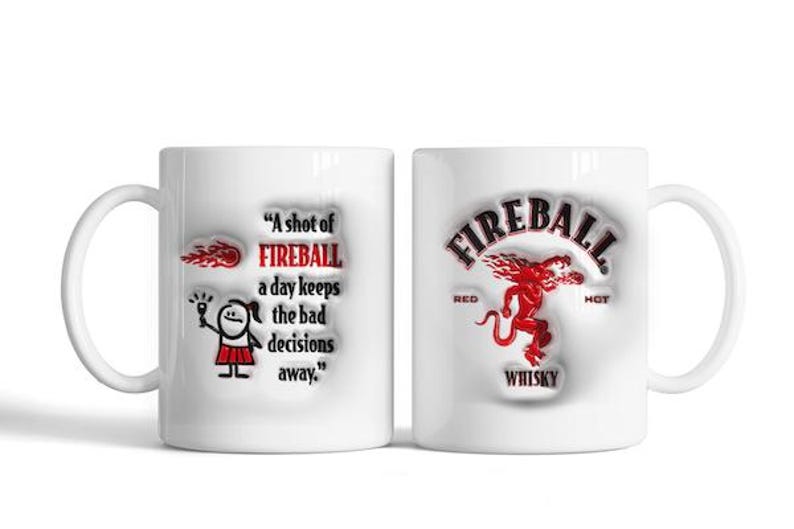 May include: White ceramic coffee mug with a red and black Fireball Whisky logo on one side and a cartoon illustration and the text "A shot of FIREBALL a day keeps the bad decisions away." on the other side.