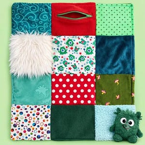 May include: A multi-textured sensory quilt featuring twelve square panels with various fabrics including teal swirls, red fleece with a zipper, green polka dots, white faux fur, monster prints, red with white dots, olive corduroy, and colorful circles.
