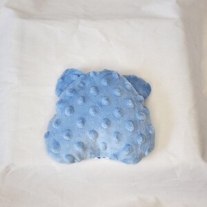 May include: A light blue, plush baby blanket with a textured, dotted surface. The blanket is a soft, cloud-like shape, perfect for a baby's comfort. The blanket is made of a soft, fuzzy material.