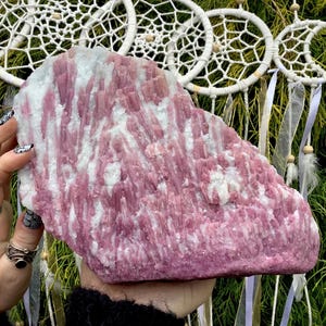 May include: A large, pink and white, raw, natural,  crystal slab with a striated pattern. The crystal is a variety of lepidolite.