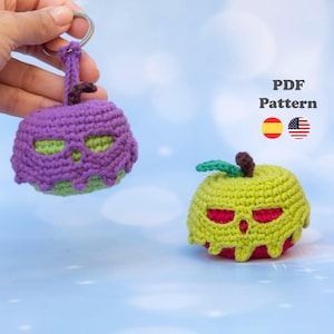 Puede incluir: Dos figuras de ganchillo con forma de manzana y caras de calavera. Una es morada con base verde claro y anilla de metal. La otra es verde claro con base roja y una pequeña hoja verde. El texto dice PDF Pattern.
