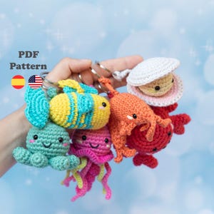 May include: A collection of colorful, crocheted sea creature keychains, including an octopus, jellyfish, fish, crab, and clam. Each keychain is attached to a silver ring. The text "PDF Pattern" is visible in the upper left corner.