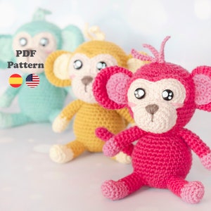 May include: Three crocheted monkey toys in different colors: teal, yellow, and pink. The monkeys have big eyes, a small nose, and a small mouth. The toys are sitting on a white surface. PDF Pattern.