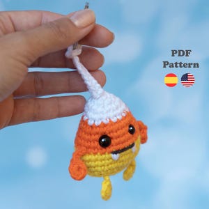 May include: A crochet candy corn monster ornament featuring a white top, orange middle, and yellow bottom with black safety eyes, a small mouth with two white teeth, and small orange and yellow limbs. The text PDF Pattern is visible.