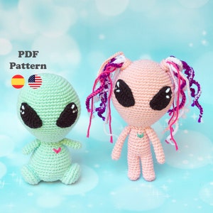 Puede incluir: Dos muñecos alienígenas de ganchillo, uno verde menta y otro melocotón, con grandes ojos negros y pequeños corazones. El alienígena melocotón tiene pelo de hilo de colores. La imagen incluye el texto "PDF Pattern" y banderas para español e inglés americano.