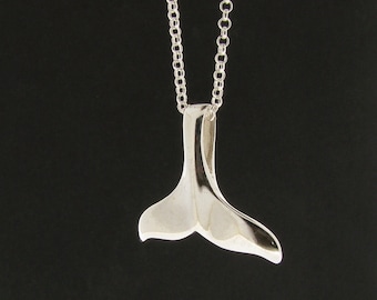 Op de afbeelding: Een zilveren ketting met een walvisstaart hanger. De staart is een eenvoudig, glad ontwerp.
