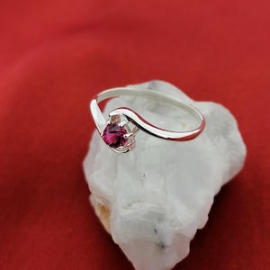 Peut inclure: Une bague en argent avec une pierre précieuse rose sertie dans une bande ondulée.