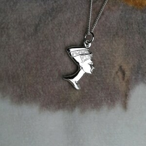 May include: Silver necklace with a pendant of the profile of an Egyptian queen wearing a headdress.