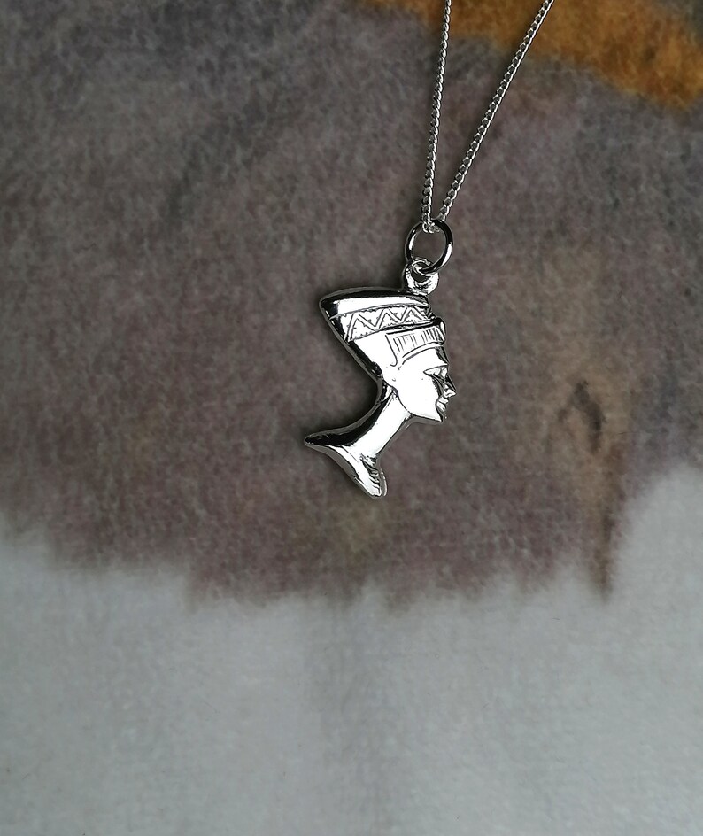 May include: Silver necklace with a pendant of the profile of an Egyptian queen wearing a headdress.