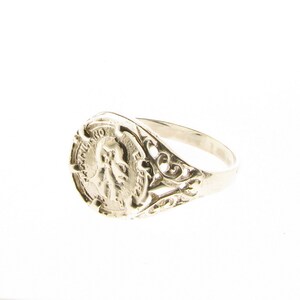 K&ouml;nnte beinhalten: Ein silberner Ring mit einem filigranen Design und einer runden, m&uuml;nzenf&ouml;rmigen Fassung mit einem Profilportr&auml;t.