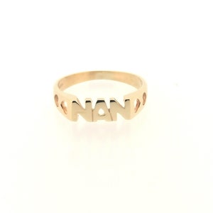 May include: Gold ring with the word "NAN" spelled out in cutout letters.