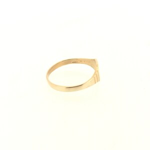 May include: A gold band ring with a textured design on the outside of the band.
