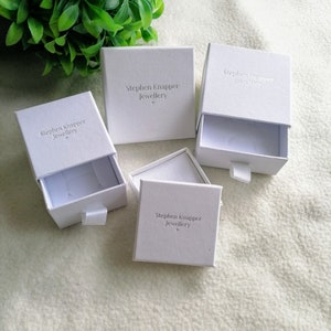 K&ouml;nnte beinhalten: Vier wei&szlig;e Schachteln mit Schublade. Jede Schachtel tr&auml;gt den Aufdruck "Stephen Knapper Jewellery".