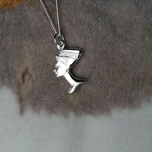 May include: Silver necklace with a pendant of the profile of an Egyptian queen wearing a headdress.