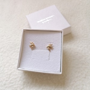 May include: A pair of gold bird stud earrings in a white box with the text "Stephen Hanna Jewellery" on the lid.