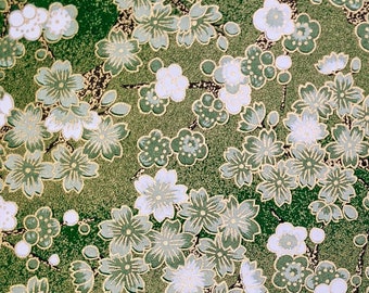Puede incluir: Tela verde con un patrón floral blanco. Las flores son pequeñas y delicadas, y están dispuestas en un patrón repetitivo. La tela tiene un brillo sutil.