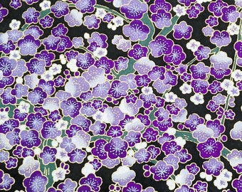 Puede incluir: Una tela negra con un patrón repetitivo de flores moradas y blancas. Las flores son estilizadas y tienen un aspecto delicado, casi como de acuarela.