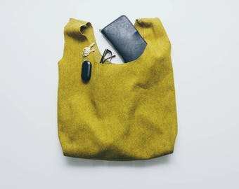 May include: A yellow fabric tote bag with a black wallet, keys, and glasses inside.