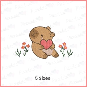 Puede incluir: Diseño bordado de un oso marrón sosteniendo un corazón rosa. Pequeñas flores rojas y amarillas con hojas verdes rodean al oso. El texto "5 Sizes" está en la parte inferior.