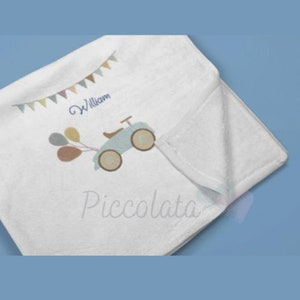May include: White baby blanket with a blue toy car and balloons, a string of colorful flags, and the name "William" embroidered on it.